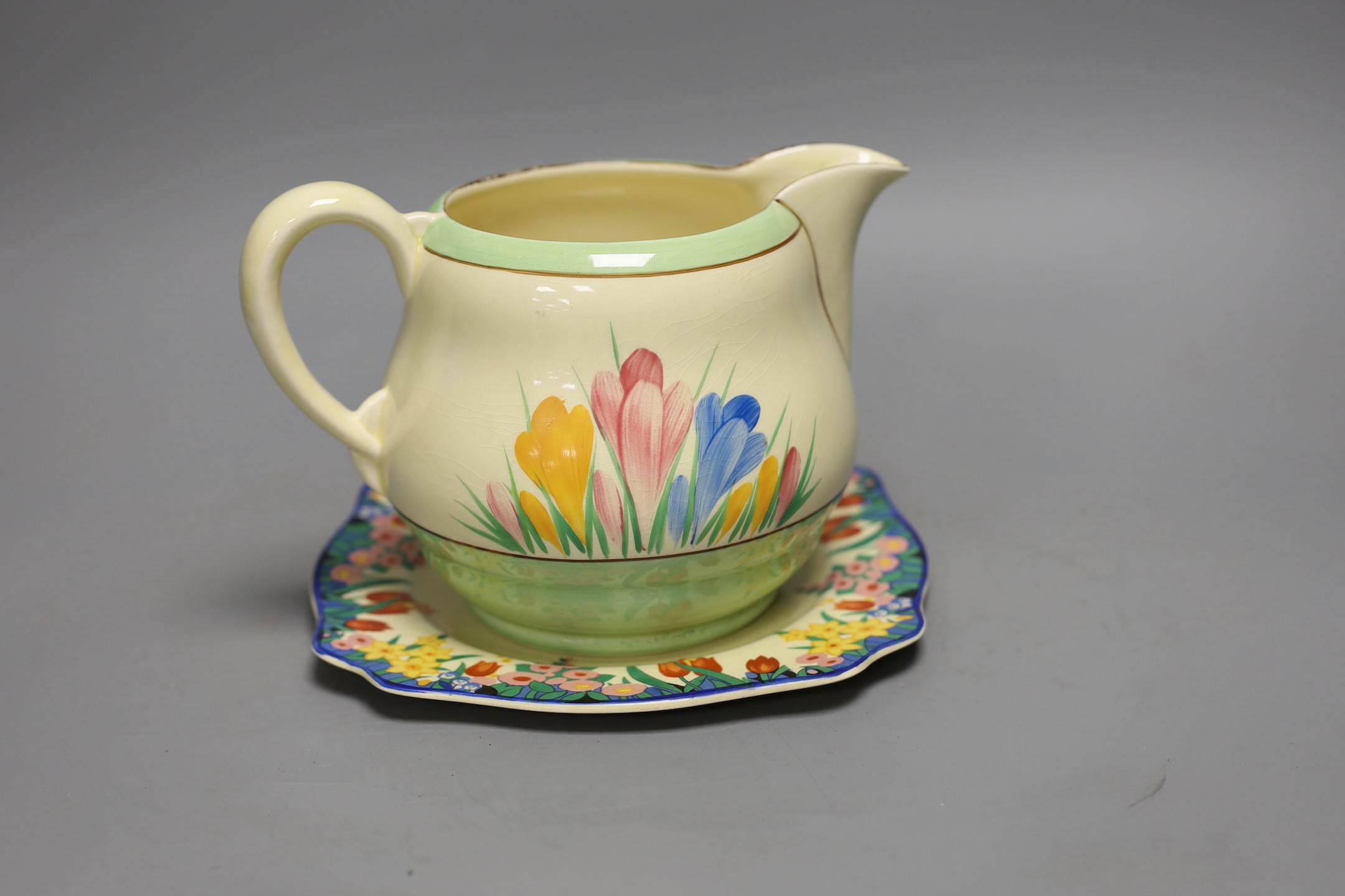 A Clarice Cliff crocus design milk jug and a Bizarre patterned side plate, jug 11.5 cms high